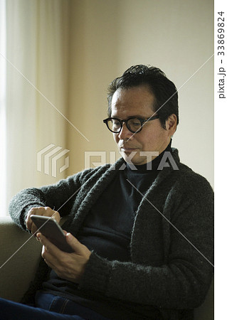 スマホを操作する60代男性 33869824