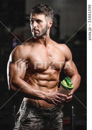 Muscular Man Resting After Exercise And Drinking From Shaker Muscular Man Resting After Exercise And Drinking From Shaker 33881096