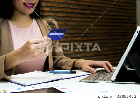 Female holding credit card and using laptop Female holding credit card and using laptop 33892432