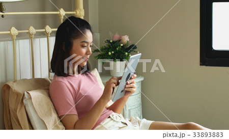 Asian pretty girl using tablet in the bedroom Asian pretty girl using tablet in the bedroom 33893883