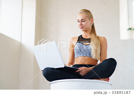 Sports girl with laptop in lotus pose 33895187