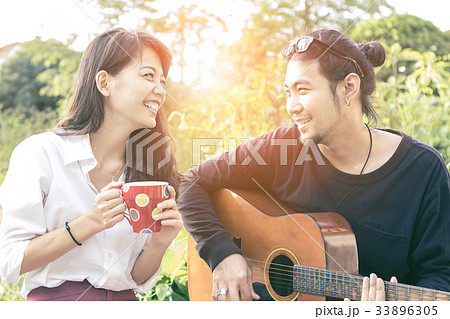 younger asian man and woman relaxing in park 33896305