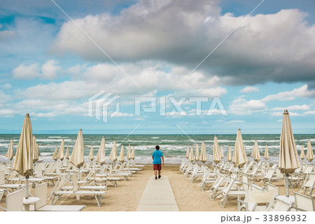 Lonely man is standing on the empty beach Lonely man is standing on the empty beach 33896932