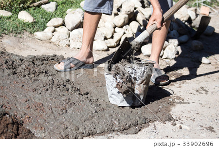 Worker stirs concrete shovel 33902696