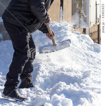 Worker cleans snow shovel 33902835