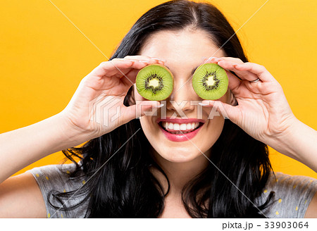 Happy young woman holding kiwis Happy young woman holding kiwis 33903064