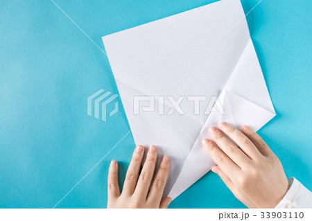 Person's hands folding a paper airplane Person's hands folding a paper airplane 33903110