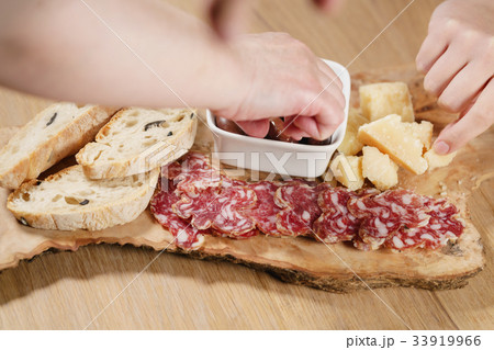hands taking italian antipasti appetizers on table 33919966
