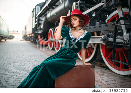 Woman in red hat against vintage steam train Woman in red hat against vintage steam train 33922736