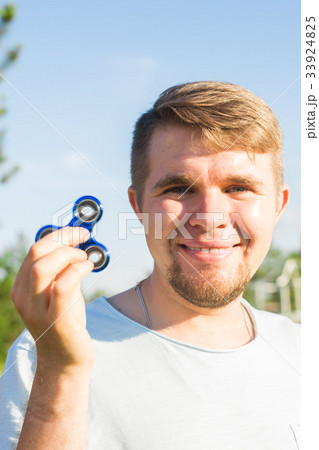 Young man holding and playing with fidget spinner Young man holding and playing with fidget spinner 33924825