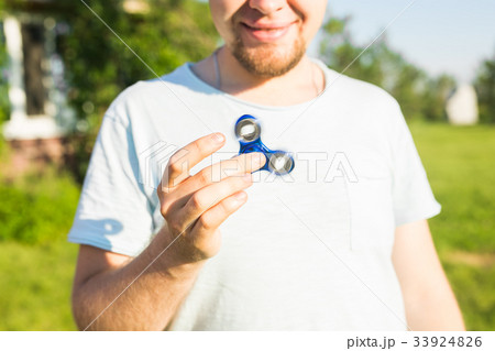 Man playing with a blue spinner fidget toy, close Man playing with a blue spinner fidget toy, close 33924826