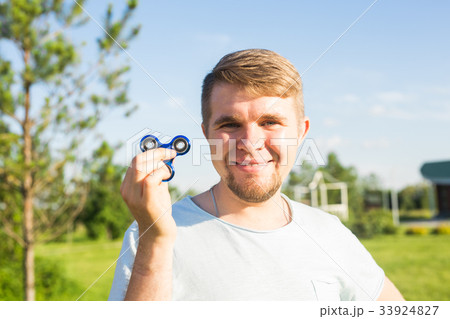 Young man holding and playing with fidget spinner Young man holding and playing with fidget spinner 33924827