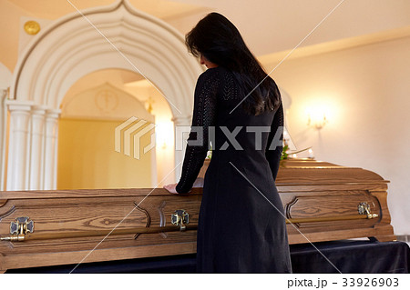 sad woman with coffin at funeral in church 33926903