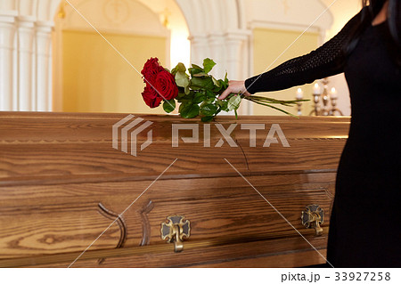 woman with red roses and coffin at funeral 33927258