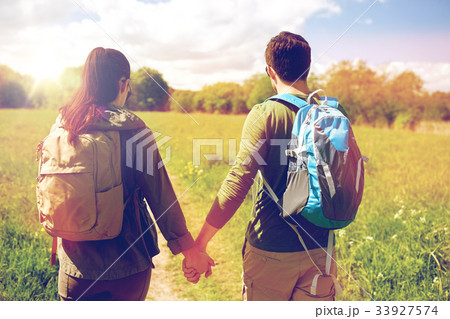 happy couple with backpacks hiking outdoors 33927574
