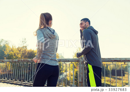 happy couple with earphones running outdoors happy couple with earphones running outdoors 33927683