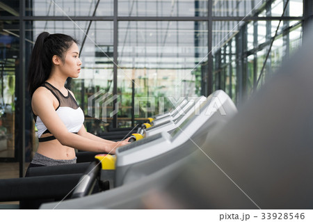 young woman execute exercise in fitness center. female athlete walking on treadmill in gym. sporty girl working out in health club. young woman execute exercise in fitness center. female athlete walking on treadmill in gym. sporty girl working out in health club. 33928546