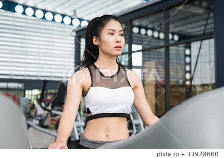 young woman execute exercise in fitness center. female athlete walking on treadmill in gym. sporty girl working out in health club. young woman execute exercise in fitness center. female athlete walking on treadmill in gym. sporty girl working out in health club. 33928600