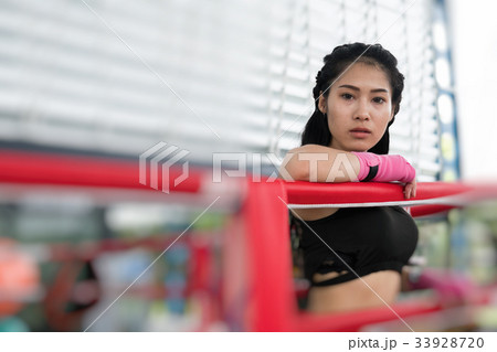 young woman prepare for exercise in fitness center. female boxer posing in boxing ring in gym. sporty girl resting after working out in health club. martial arts, muay thai concept young woman prepare for exercise in fitness center. female boxer posing in boxing ring in gym. sporty girl resting after working out in health club. martial arts, muay thai concept 33928720