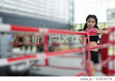 young woman prepare for exercise in fitness center. female boxer posing in boxing ring in gym. sporty girl resting after working out in health club. martial arts, muay thai concept young woman prepare for exercise in fitness center. female boxer posing in boxing ring in gym. sporty girl resting after working out in health club. martial arts, muay thai concept 33928724