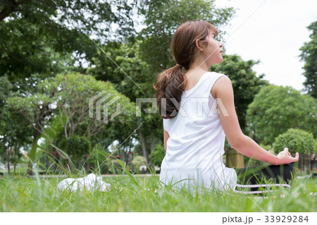 Yoga outdoors in public park. Asian woman sits in lotus position. Young female with zen gesturing. healthy lifestyle and relaxation concept Yoga outdoors in public park. Asian woman sits in lotus position. Young female with zen gesturing. healthy lifestyle and relaxation concept 33929284