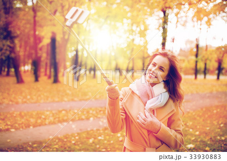 woman taking selfie by smartphone in autumn park 33930883