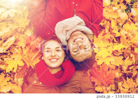 close up of smiling couple lying on autumn leaves 33930912