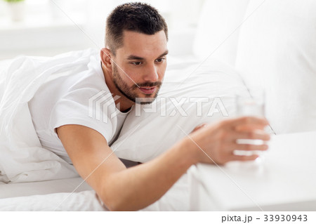 man in bed with glass of water at home man in bed with glass of water at home 33930943