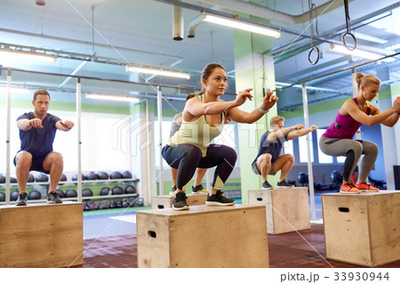 group of people doing box jumps exercise in gym group of people doing box jumps exercise in gym 33930944