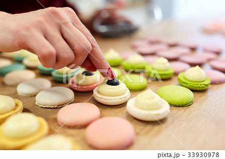 chef decorating macarons shells at pastry shop 33930978