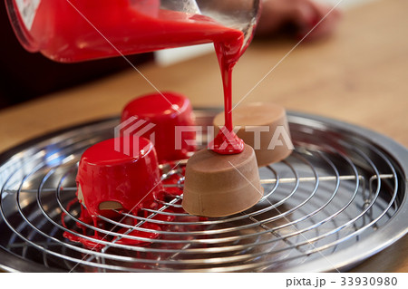 jug pouring glaze to cakes at pastry shop 33930980