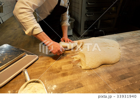 baker portioning dough with bench cutter at bakery baker portioning dough with bench cutter at bakery 33931940