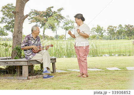 A picture of an elderly couple playing guitar and dancing in a park 33936852