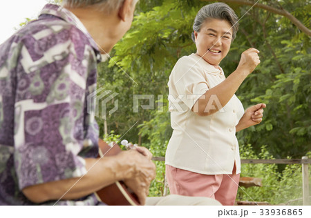 an old woman is standing and smiling with her husband in the park 33936865