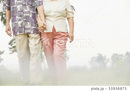an old couple is holding hand each other and walking together 33936873