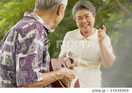 a senior man is playing guitar and his grandchild is dancing at balcony 33936909