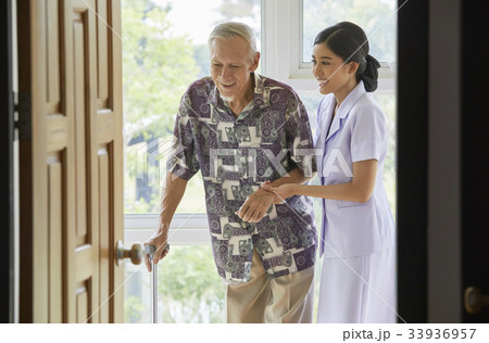 a nurse and senior man are smiling and walking indoors 33936957