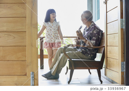 senior man is playing guitar and his granddaughter is singing 33936967
