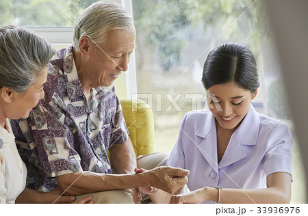 a nurse is checking the pulse of senior patient 33936976