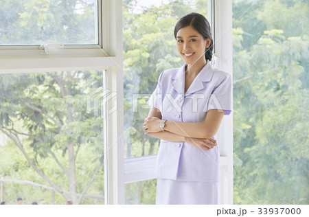 A nurse is crossing her arms and smiling beside the glass window A nurse is crossing her arms and smiling beside the glass window 33937000