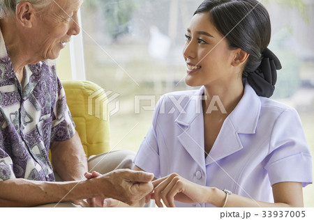 A senior man is smiling to a nurse and looking at her 33937005