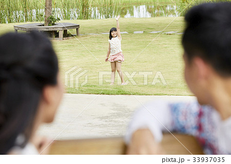 A little girl is waving her parents outdoors 33937035