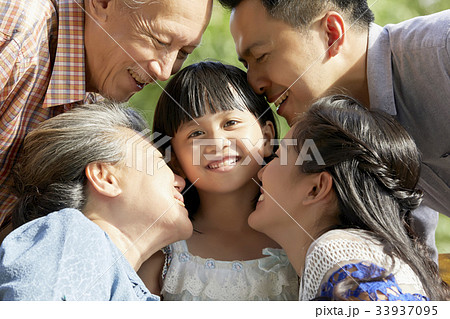 A little girl is smiling while having fun with her parents and her grandparents. A little girl is smiling while having fun with her parents and her grandparents. 33937095