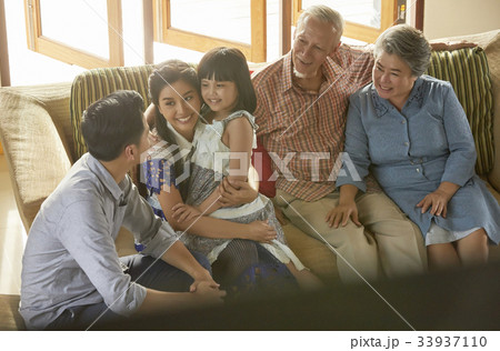 an extended family is sitting on a sofa and having fun together. an extended family is sitting on a sofa and having fun together. 33937110
