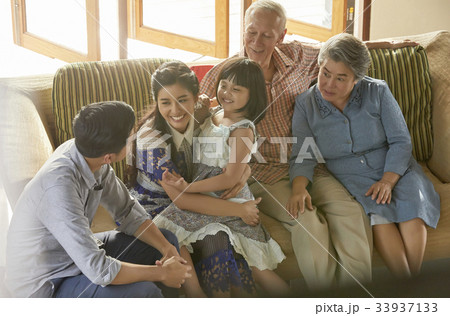 an extended family is gathering on a sofa and having fun together. an extended family is gathering on a sofa and having fun together. 33937133