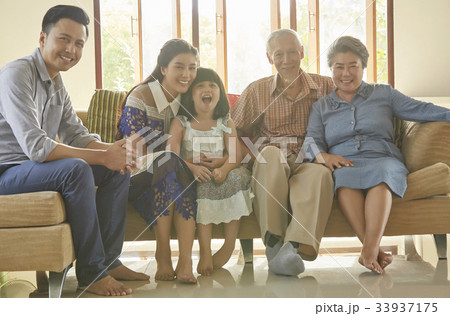 an extended family is sitting inside of the house and smiling happily an extended family is sitting inside of the house and smiling happily 33937175