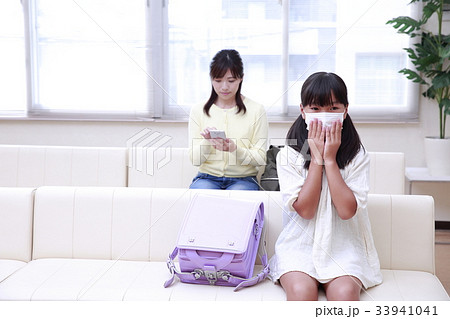 待合室で診察を待つマスクをした小学生と女性 33941041