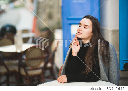 Beautiful young woman posing on the street in old 33945645