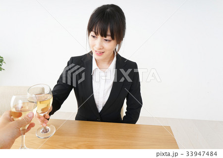 スーツ姿でお酒を飲む若い女性 スーツ姿でお酒を飲む若い女性 33947484