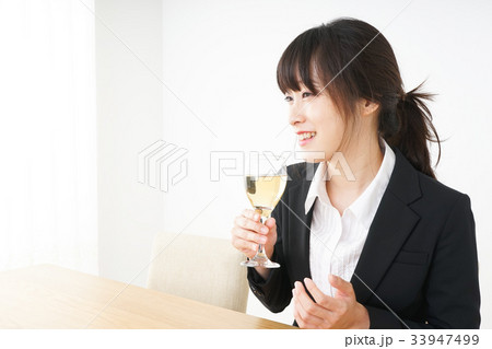 スーツ姿でお酒を飲む若い女性 スーツ姿でお酒を飲む若い女性 33947499